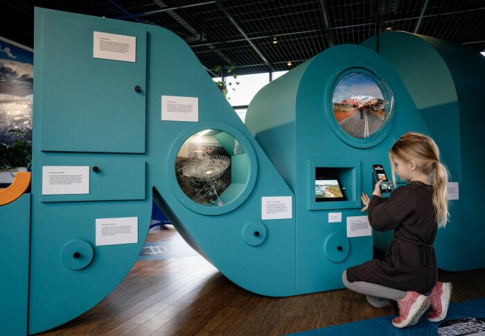 A young visitor takes a photo of NWO’s interactive exhibition, Milestones of 75 Years of Science